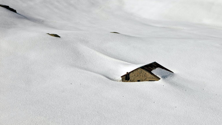 Von Flugschnee verschneite Berghütte